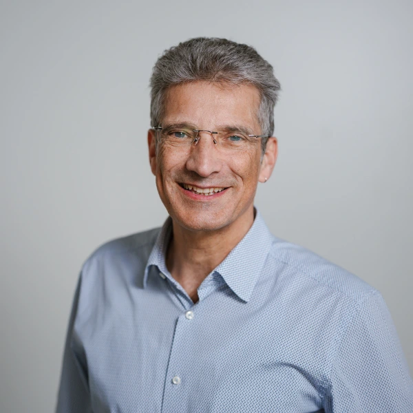 Antonio Krüger standing infront of a white wall and looking into the camera.